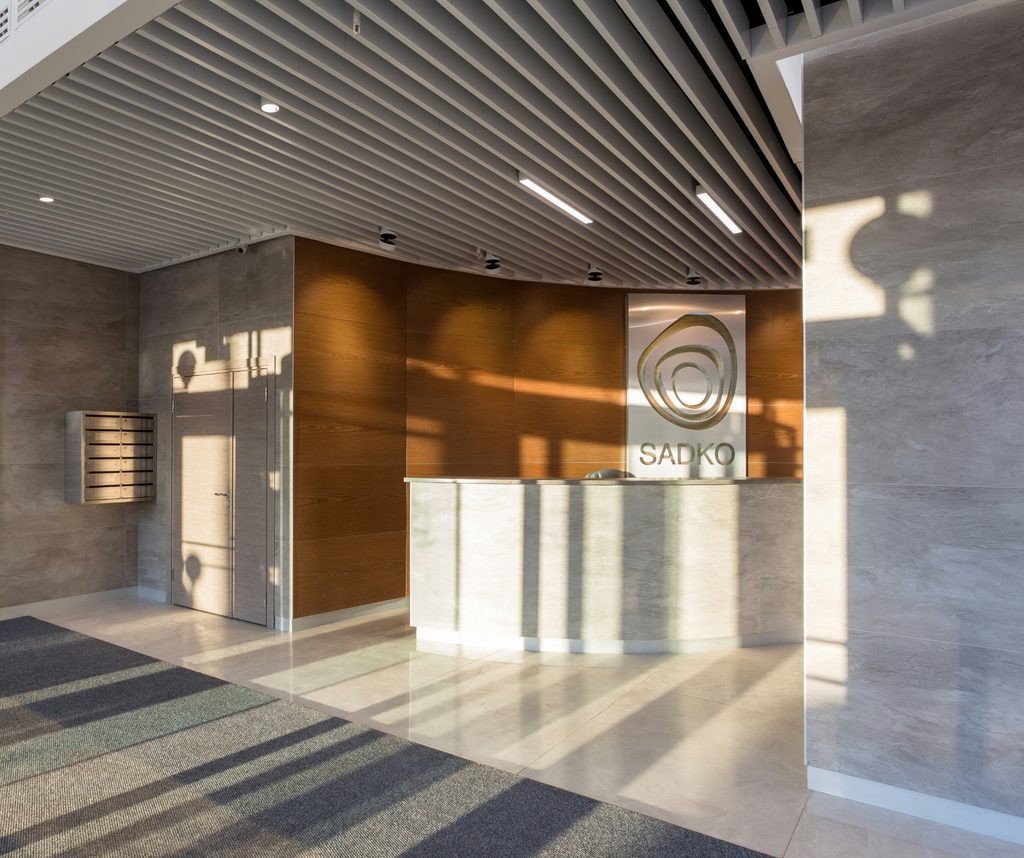 Modern office building lobby with a reception desk and wood-panelled walls